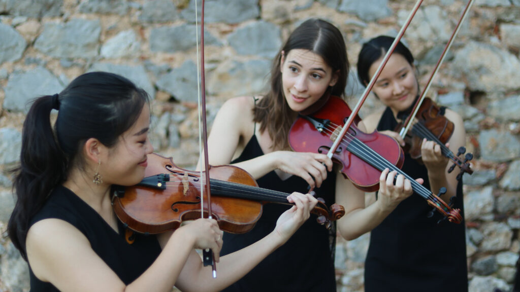 Drei Damen in festlicher Robe spielen Violine